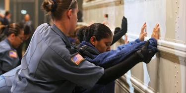 TO GO WITH AFP STORY BY CARLOS MARIO MARQUEZ A prison guard frisks a female detainee before embarking onto a bus to be taken to the airport at Willacy Detention facility in Raymondville, Texas on December 18, 2008 early morning. The Willacy facility is used by the US Immigration and Customs Enforcement agency (ICE) to keep illegal immigrants in detention before they are deported. Today, 116 Salvadorean nationals --83 men and 33 women-- were woken up at 4 a.m. and transported in buses under strict surveillance to Harlengen's airport to be taken back to El Salvador.  AFP PHOTO/ Jose CABEZAS (Photo credit should read Jose CABEZAS/AFP/Getty Images)