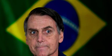Brazil's right-wing presidential candidate for the Social Liberal Party (PSL) Jair Bolsonaro gestures in front of the Brazilian flag as he prepares to cast his vote during the general elections, in Rio de Janeiro, Brazil, on October 7, 2018. - Polling stations opened in Brazil on Sunday for the most divisive presidential election in the country in years, with far-right lawmaker Jair Bolsonaro the clear favorite in the first round. About 147 million voters are eligible to cast ballots and choose who will rule the world's eighth biggest economy. New federal and state legislatures will also be elected. (Photo by Mauro PIMENTEL / AFP)        (Photo credit should read MAURO PIMENTEL/AFP/Getty Images) Brazil's right-wing presidential candidate for the Social Liberal Party (PSL) Jair Bolsonaro gestures in front of the Brazilian flag as he prepares to cast his vote during the general elections, in Rio de Janeiro, Brazil, on October 7, 2018. - Polling stations opened in Brazil on Sunday for the most divisive presidential election in the country in years, with far-right lawmaker Jair Bolsonaro the clear favorite in the first round. About 147 million voters are eligible to cast ballots and choose who will rule the world's eighth biggest economy. New federal and state legislatures will also be elected. (Photo by Mauro PIMENTEL / AFP)        (Photo credit should read MAURO PIMENTEL/AFP/Getty Images)