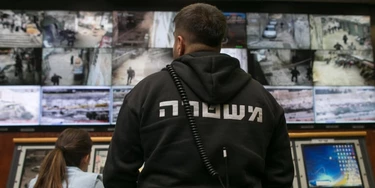 People observe surveillance cameras on screens inside the Jerusalem Police's Mabat 2000 unit.