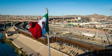 Vista aérea da bandeira do México sobre uma ponte internacional enquanto migrantes chegam à cerca da fronteira Estados Unidos para buscar asilo em 2022.