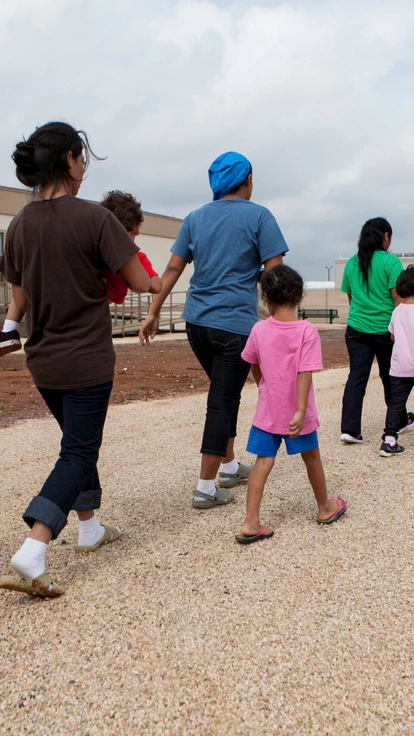 DILLEY, TEXAS - May 14, 2015: Residents walk through the facility grounds to eat lunch at the cafeteria. The South Texas Family Residential Center in Dilley, Texas was built in December 2014 to host up to 2,400 undocumented women and children who are seeking asylum. The Dilley facility is the largest of its kind, and while residents may move freely from building to building, they are not permitted to leave the grounds. DILLEY, TEXAS - May 14, 2015: Residents walk through the facility grounds to eat lunch at the cafeteria. The South Texas Family Residential Center in Dilley, Texas was built in December 2014 to host up to 2,400 undocumented women and children who are seeking asylum. The Dilley facility is the largest of its kind, and while residents may move freely from building to building, they are not permitted to leave the grounds.