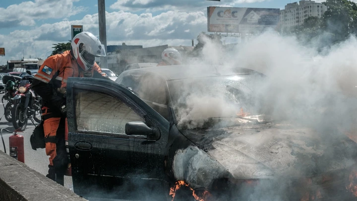 Bombeiro apaga incêndio em carro acidentado na Avenida Brasil, no Rio de Janeiro, em 2017.