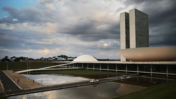BRASILIA, BRAZIL - OCTOBER 27:  People linger in front of the Brazilian National Congress building on October 27, 2014 in Brasilia, Brazil. Brazil's left-wing President Dilma Rousseff was narrowly re-elected yesterday and will serve another four years in Brazil's unique planned capital city. The modernist city was founded in 1960 and replaced Rio de Janeiro as the federal capital of Brazil. The city was designed by urban planner Lucio Costa and architect Oscar Niemeyer and is now a UNESCO World Hertiage site.  (Photo by Mario Tama/Getty Images)