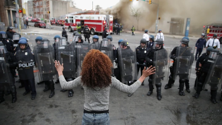 BALTIMORE, MD - APRIL 27:  A woman faces down a line of Baltimore Police officers in riot gear during violent protests following the funeral of Freddie Gray April 27, 2015 in Baltimore, Maryland. Gray, 25, who was arrested for possessing a switch blade knife April 12 outside the Gilmor Homes housing project on Baltimore's west side. According to his attorney, Gray died a week later in the hospital from a severe spinal cord injury he received while in police custody.  (Photo by Chip Somodevilla/Getty Images) BALTIMORE, MD - APRIL 27:  A woman faces down a line of Baltimore Police officers in riot gear during violent protests following the funeral of Freddie Gray April 27, 2015 in Baltimore, Maryland. Gray, 25, who was arrested for possessing a switch blade knife April 12 outside the Gilmor Homes housing project on Baltimore's west side. According to his attorney, Gray died a week later in the hospital from a severe spinal cord injury he received while in police custody.  (Photo by Chip Somodevilla/Getty Images)