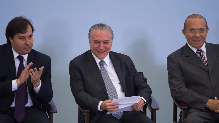 Brazilian President Michel Temer (C), Lower House President Rodrigo Maia and Chief of Staff Eliseu Padilha (R) attend a ceremony to promote new economy laws at Plantalto palace on October 27, 2016.Temer, who took over after the impeachment of Dilma Rousseff in August, urged an oil and gas conference in Rio de Janeiro to join what he said was an economy on the mend. / AFP / ANDRESSA ANHOLETE (Photo credit should read ANDRESSA ANHOLETE/AFP/Getty Images)