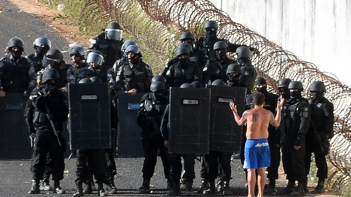 Riot police agents group and approach to negociate with an inmate's delegate (R) during a rebellion at the Alcacuz Penitentiary Center near Natal, Rio Grande do Norte state, northeastern Brazil on January 16, 2017.The latest in a string of brutal prison massacres involving suspected gang members in Brazil has killed 26 inmates, most of whom were beheaded. The bloodbath erupted Saturday night in the overcrowded Alcacuz prison in the northeastern state of Rio Grande do Norte. Similar violence at other jails in Brazil left around 100 inmates dead in early January. / AFP / ANDRESSA ANHOLETE (Photo credit should read ANDRESSA ANHOLETE/AFP/Getty Images)