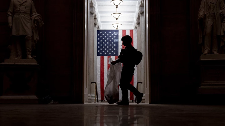 An ATF police officer cleans up debris and personal belongings strewn across the floor of the Rotunda in the early morning hours of Thursday, Jan. 7, 2021, after protesters stormed the Capitol in Washington, on Wednesday. (AP Photo/Andrew Harnik)