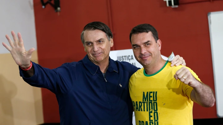 FILE - In this Oct. 7, 2018 file photo, then presidential frontrunner Jair Bolsonaro, left, and his son Flavio, acknowledge reporters at a polling station in Rio de Janeiro, Brazil. The son of Brazilian President-elect Jair Bolsonaro is denying wrongdoing in a case involving suspect bank transactions. According to a recent Financial Activities Control Council report, Flavio Bolsonaro's driver deposited various amounts between January 2016 and January 2017. On Thursday, Dec. 13, 2018, Flavio Bolsonaro posted on Twitter that he had “done nothing wrong.” (AP Photo/Silvia Izquierdo, File) FILE - In this Oct. 7, 2018 file photo, then presidential frontrunner Jair Bolsonaro, left, and his son Flavio, acknowledge reporters at a polling station in Rio de Janeiro, Brazil. The son of Brazilian President-elect Jair Bolsonaro is denying wrongdoing in a case involving suspect bank transactions. According to a recent Financial Activities Control Council report, Flavio Bolsonaro's driver deposited various amounts between January 2016 and January 2017. On Thursday, Dec. 13, 2018, Flavio Bolsonaro posted on Twitter that he had “done nothing wrong.” (AP Photo/Silvia Izquierdo, File)
