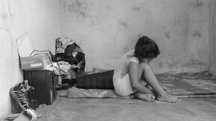 Migrante de 10 anos, que fugiu de ameaças de gangues de El Salvador, senta-se sobre os lençóis que sua família usa como cama em uma casa alugada em Tapachula, Chiapas.
