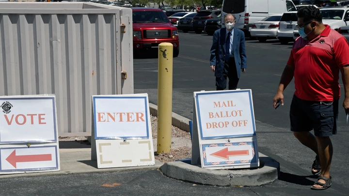 Pessoas caminham seguindo os cartazes enquanto se dirigem ao Departamento Eleitoral do Condado de Clark, que serve como ponto de votação principal nas eleições e como centro de votação presencial em meio à pandemia de coronavírus em 9 de junho de 2020, em North Las Vegas, Nevada.