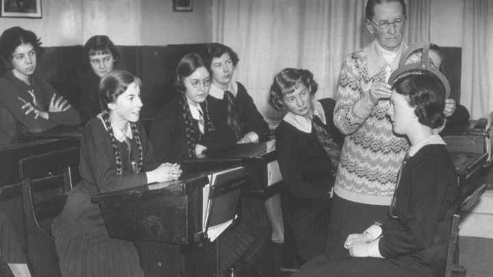 circa 1937:  A phrenologist, who reads the 'bumps' on people's heads,  demonstrating how to measure a head to a class of schoolgirls.  (Photo by Hulton Archive/Getty Images)