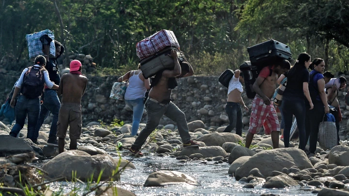 People taking irregular roads cross the Tachira river from Cucuta in Colombia to San Antonio del Tachira in Venezuela, near the Simon Bolivar international Bridge, on February 25, 2019. - United States Vice President Mike Pence told Venezuelan opposition leader Juan Guaido that Donald Trump supports him "100 percent" as the pair met regional allies on Monday to thrash out a strategy to remove Nicolas Maduro from power after the failed attempt to ship in humanitarian aid. (Photo by Luis ROBAYO / AFP)        (Photo credit should read LUIS ROBAYO/AFP/Getty Images)