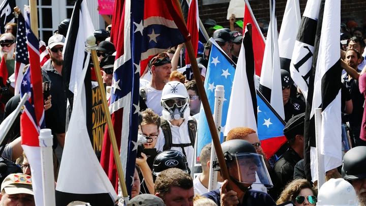 White nationalist demonstrators walk into the entrance of Lee Park surrounded by counter demonstrators in Charlottesville, Va., Saturday, Aug. 12, 2017. Gov. Terry McAuliffe declared a state of emergency and police dressed in riot gear ordered people to disperse after chaotic violent clashes between white nationalists and counter protestors. (AP Photo/Steve Helber)