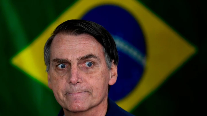 Brazil's right-wing presidential candidate for the Social Liberal Party (PSL) Jair Bolsonaro gestures in front of the Brazilian flag as he prepares to cast his vote during the general elections, in Rio de Janeiro, Brazil, on October 7, 2018. - Polling stations opened in Brazil on Sunday for the most divisive presidential election in the country in years, with far-right lawmaker Jair Bolsonaro the clear favorite in the first round. About 147 million voters are eligible to cast ballots and choose who will rule the world's eighth biggest economy. New federal and state legislatures will also be elected. (Photo by Mauro PIMENTEL / AFP)        (Photo credit should read MAURO PIMENTEL/AFP/Getty Images)