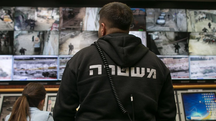 People observe surveillance cameras on screens inside the Jerusalem Police's Mabat 2000 unit.