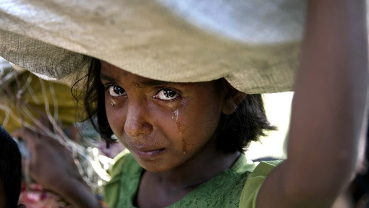 PALONG KHALI, BANGLADESH - OCTOBER 16: A Rohingya girl cries as refugees fleeing from Myanmar cross a stream in the hot sun on a muddy rice field on October 16, 2017 near Palang Khali, Cox's Bazar, Bangladesh. Well over a half a million Rohingya refugees have fled into Bangladesh since late August during the outbreak of violence in Rakhine state causing a humanitarian crisis in the region with continued challenges for aid agencies. (Photo by Paula Bronstein/Getty Images)