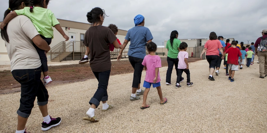 DILLEY, TEXAS - May 14, 2015: Residents walk through the facility grounds to eat lunch at the cafeteria. The South Texas Family Residential Center in Dilley, Texas was built in December 2014 to host up to 2,400 undocumented women and children who are seeking asylum. The Dilley facility is the largest of its kind, and while residents may move freely from building to building, they are not permitted to leave the grounds.