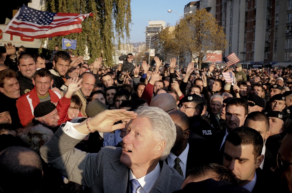 Former US President Bill Clinton (C, front) gestures as he greets Kosovo citizens during his visit in Pristina on November 1, 2009. Kosovo Albanians, who admire Clinton because of his role in the 1999 NATO bombings of then Yugoslavian President Slobodan Milosevic, honoured him by erecting a three-metre (10-feet) tall monument on a Pristina boulevard already named after him. AFP PHOTO/ARMEND NIMANI (Photo credit should read Armend Nimani/AFP/Getty Images)